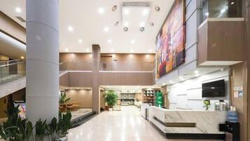 Un vestíbulo de hotel con mostrador de recepción, zona de estar y una escalera.