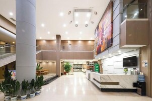 A hotel lobby with a reception desk, seating area, and a staircase.