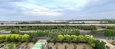 An aerial view of a parking lot with multiple rows of parked cars, surrounded by trees and greenery.