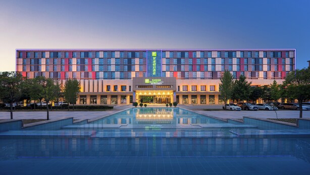 Een meerlaags hotel met een zwembad op de voorgrond.