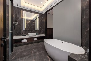 A modern bathroom with a freestanding bathtub, dark marble flooring, and a large mirror above the sink. - Holiday Inn Express Zhengzhou Airport by IHG (Zhengzhou)