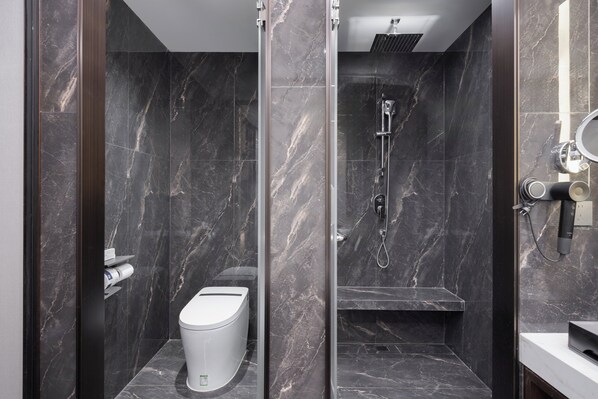 Un baño moderno con inodoro, ducha y un revestimiento de mármol.
