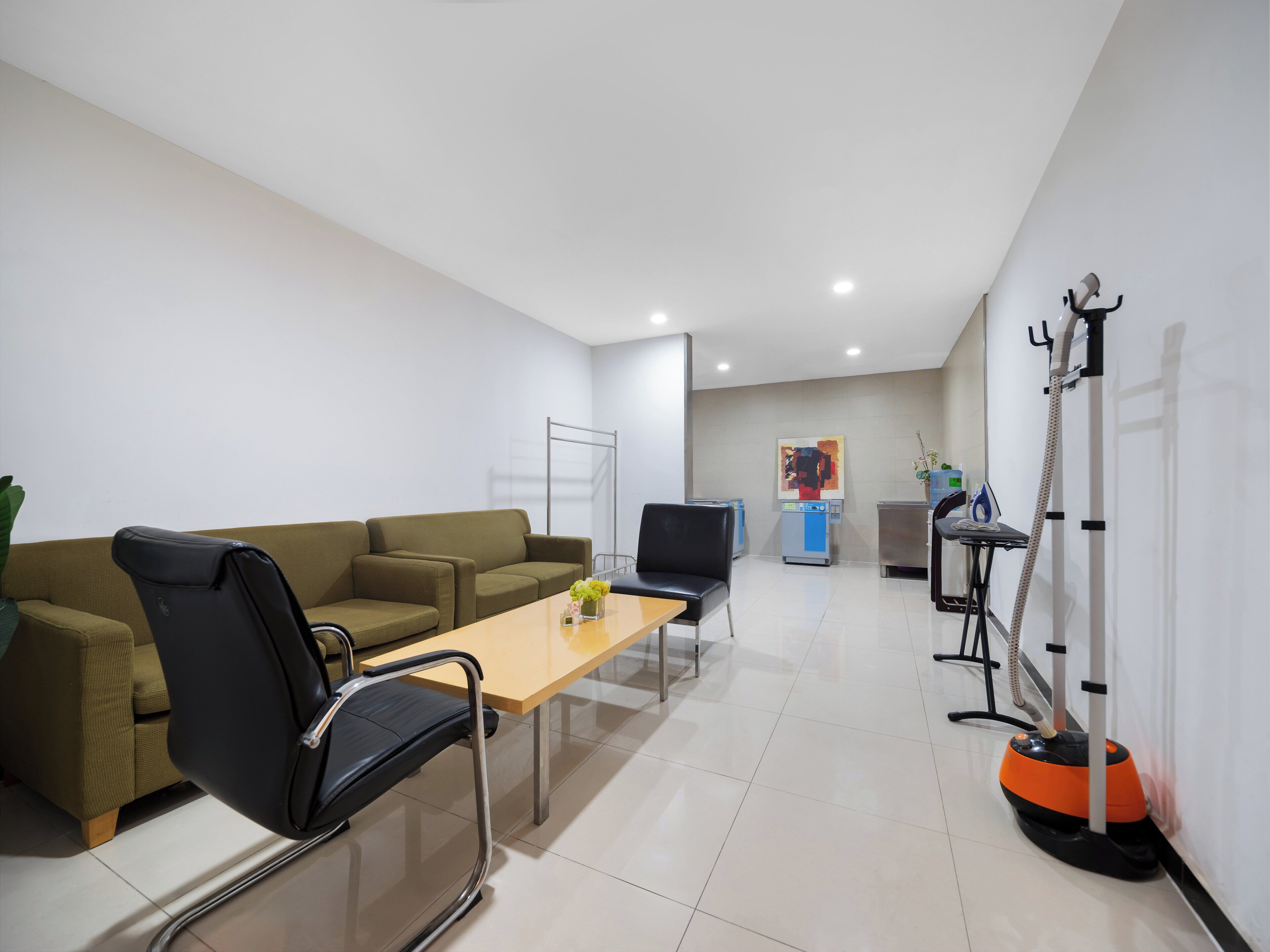 Un área de espera moderna con un sofá, sillas, una mesa, dispensador de agua y un aspirador.