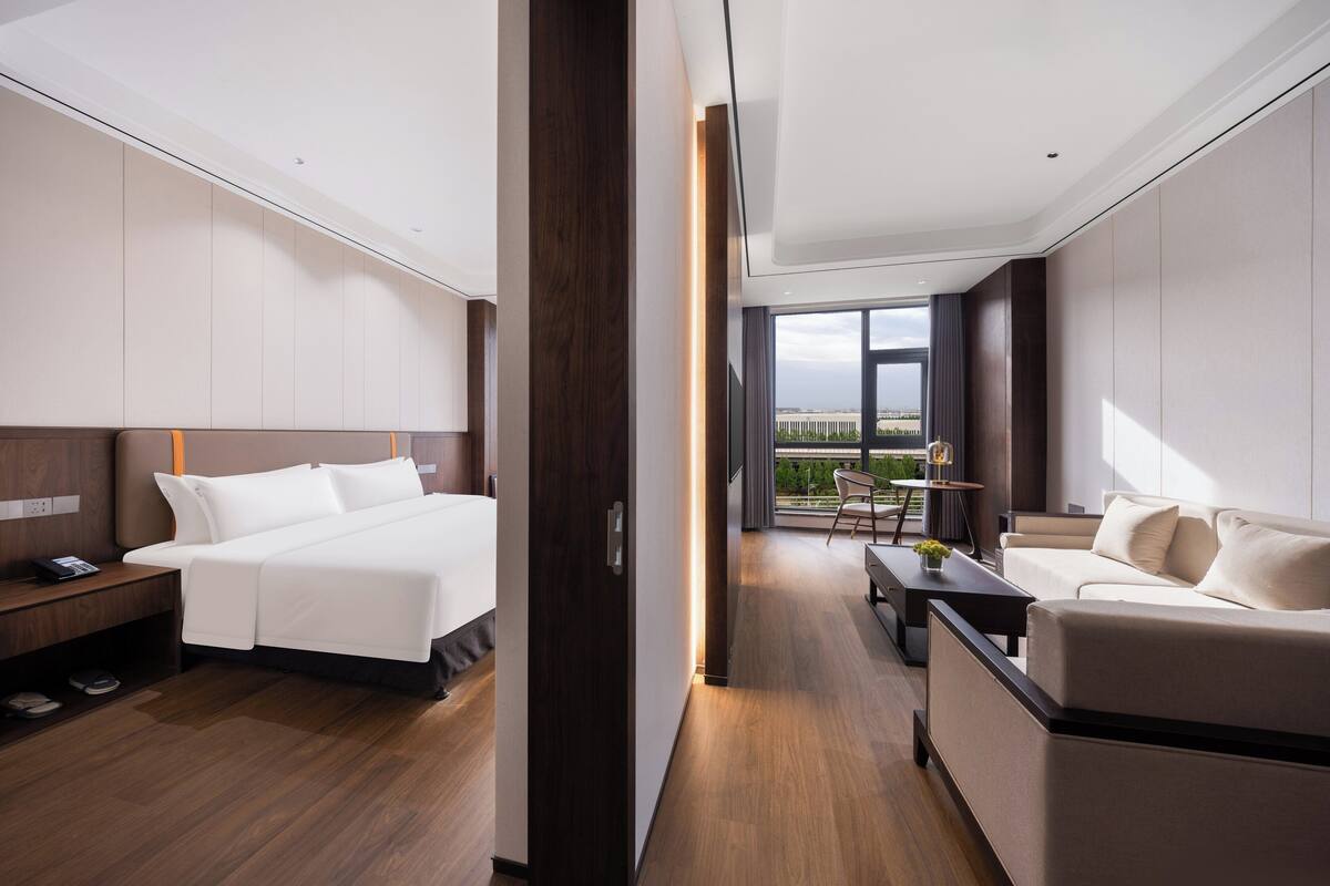 Ett modernt hotellrum med en stor säng, en soffa, ett skrivbord och utsikt över staden.
