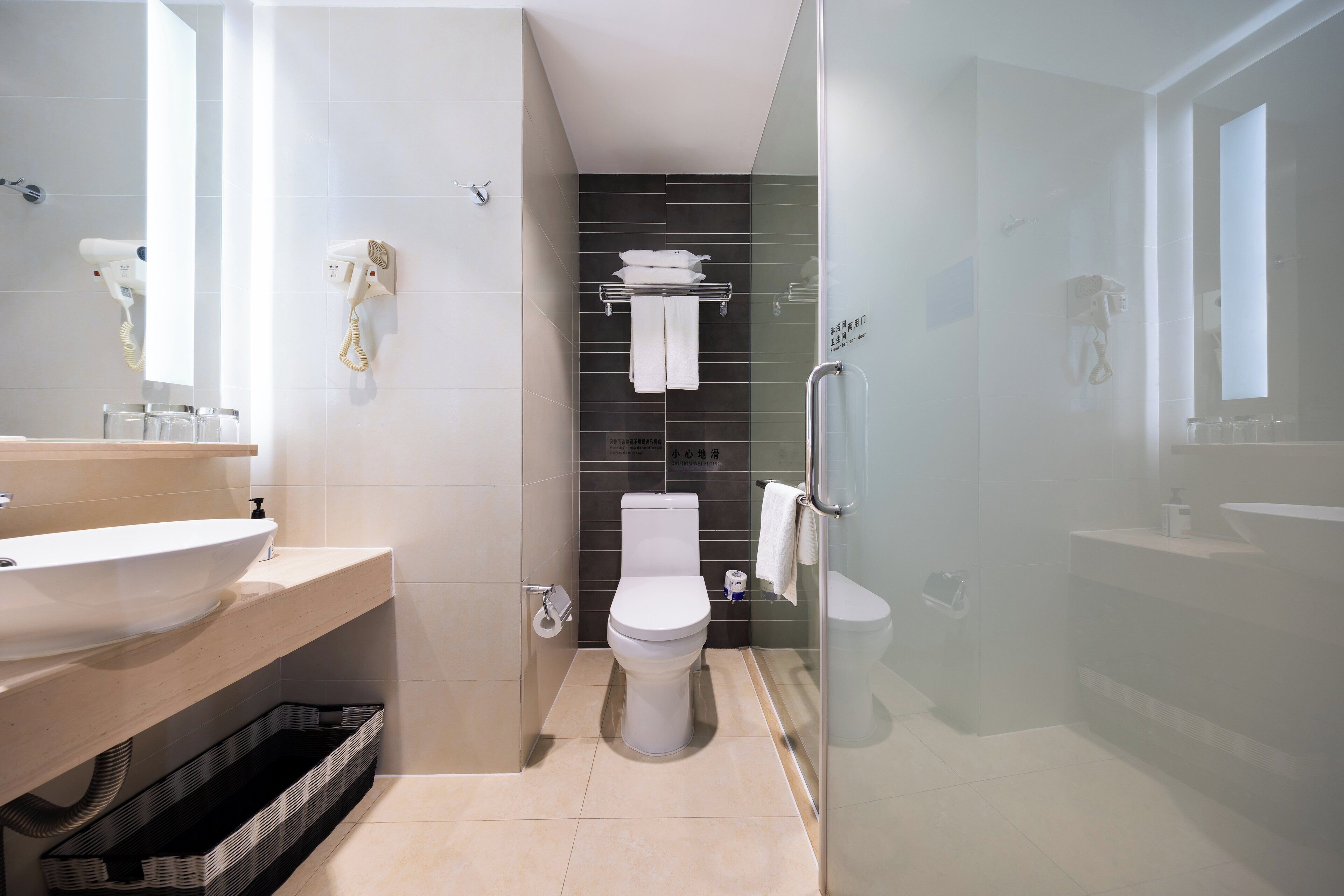 Een moderne badkamer met een groot wastafel, toilet en een douchecabine met glazen wanden.