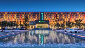 Een hotel met een groot, reflecterend zwembad ervoor, een moderne gevel en een bord waarop staat dat het een Holiday Inn Express is.