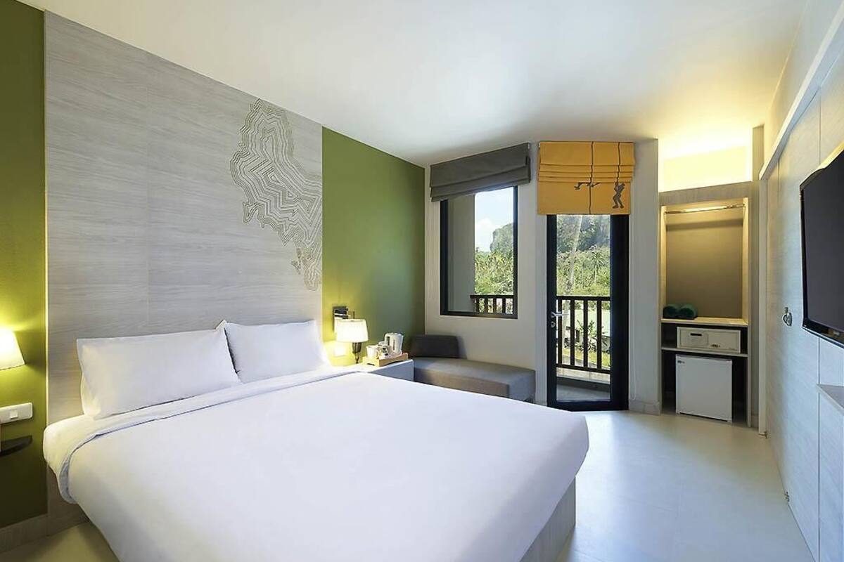 Une chambre d’hôtel avec un grand lit, un bureau, une chaise, une télévision et un balcon avec vue.