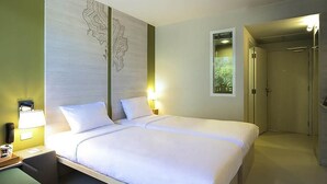 A hotel room with a large bed, bedside lamps, a nightstand, and a view of a door leading to another room. - ibis Styles Krabi Ao Nang (Krabi)