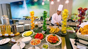 A buffet with various food items and a chef preparing food. - ibis Styles Krabi Ao Nang (Krabi)