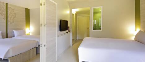 A hotel room with two beds, a television, a door, and a window with blinds.