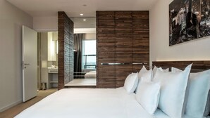 A modern bedroom with a large bed, wooden panel walls, and a city view. - Radisson Collection Hotel, Old Mill Belgrade (Belgrade)
