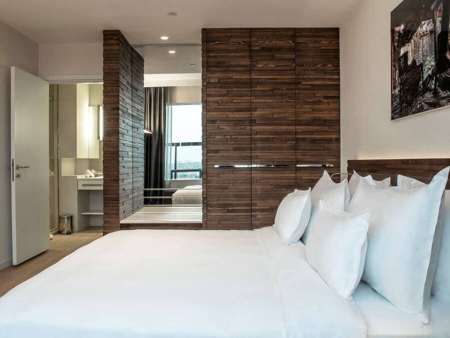 Un dormitorio moderno con una cama grande, paneles de madera y vista a la ciudad.