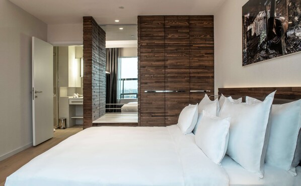 A modern bedroom with a large bed, wooden panel walls, and a city view.