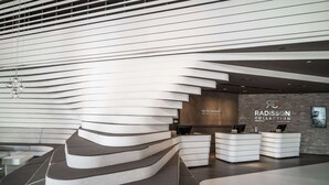 A modern reception area with a curved seating arrangement, a reception desk, and a wall displaying the Radisson Collection logo. - Radisson Collection Hotel, Old Mill Belgrade (Belgrade)