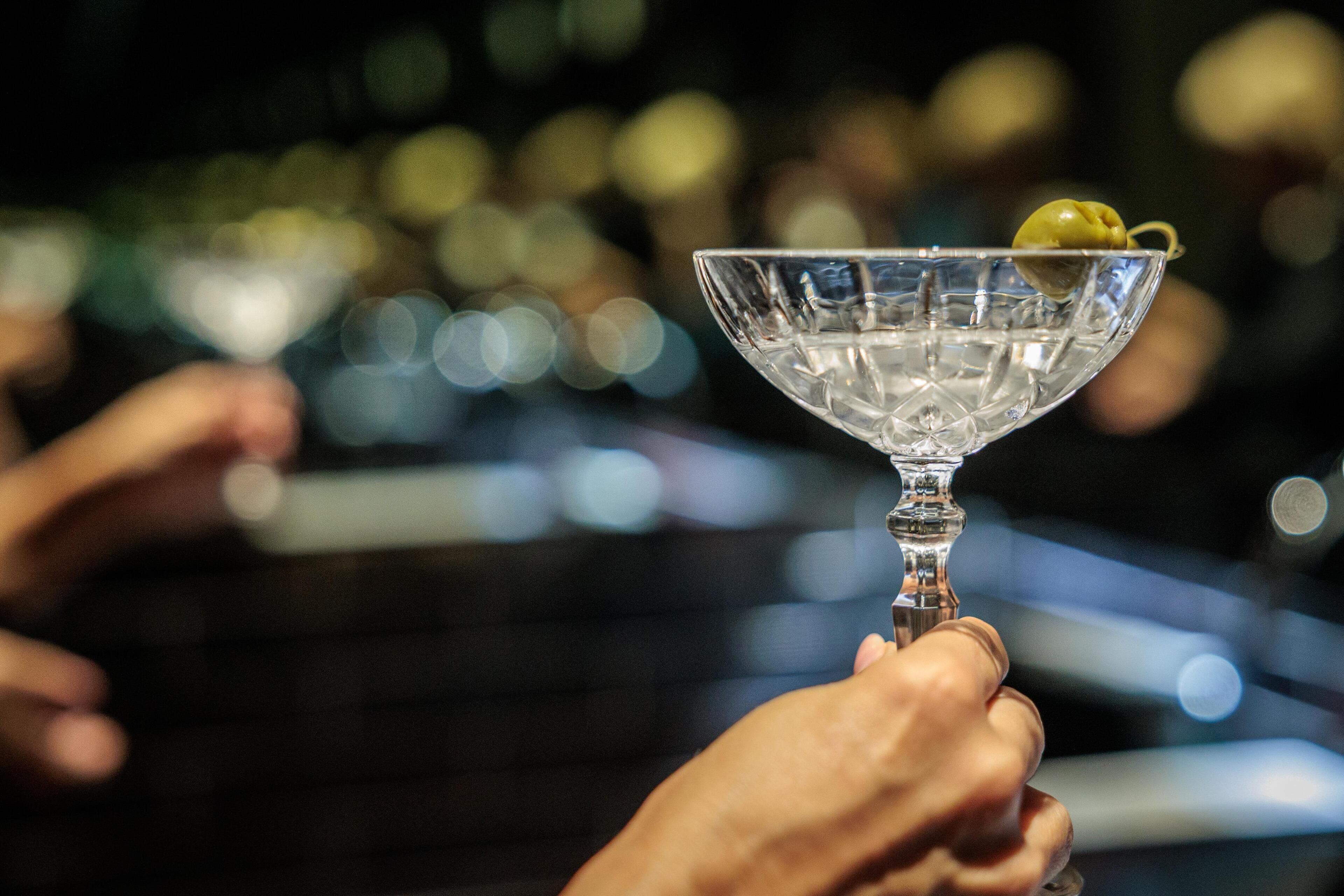 A martini glass with a lime wedge on a bar.