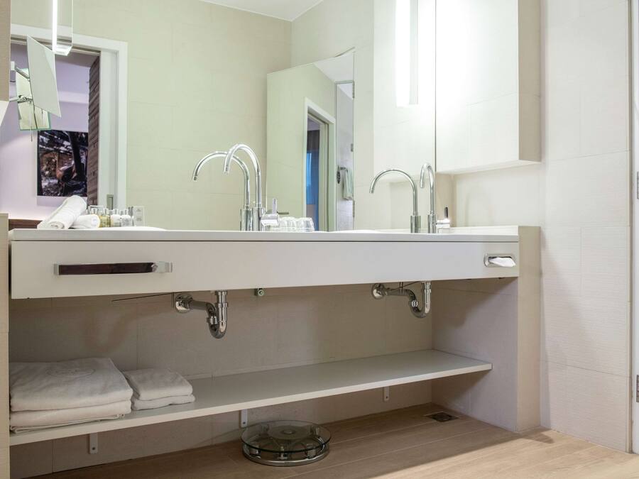 Un bagno moderno con un ampio specchio, due lavabi e un portasciugamani.