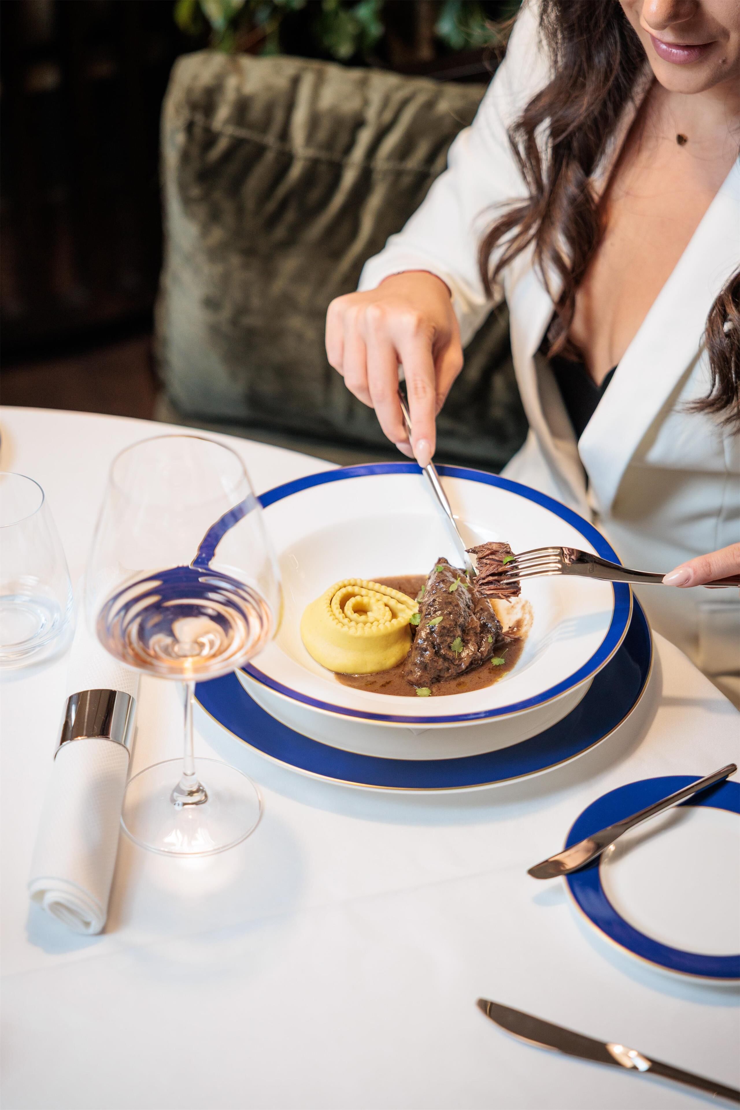 Un tavolo da pranzo con un piatto di cibo, un bicchiere di vino e posate.