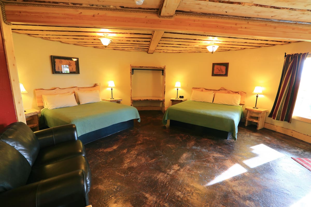 A room with two beds, wooden ceiling beams, and two bedside lamps.
