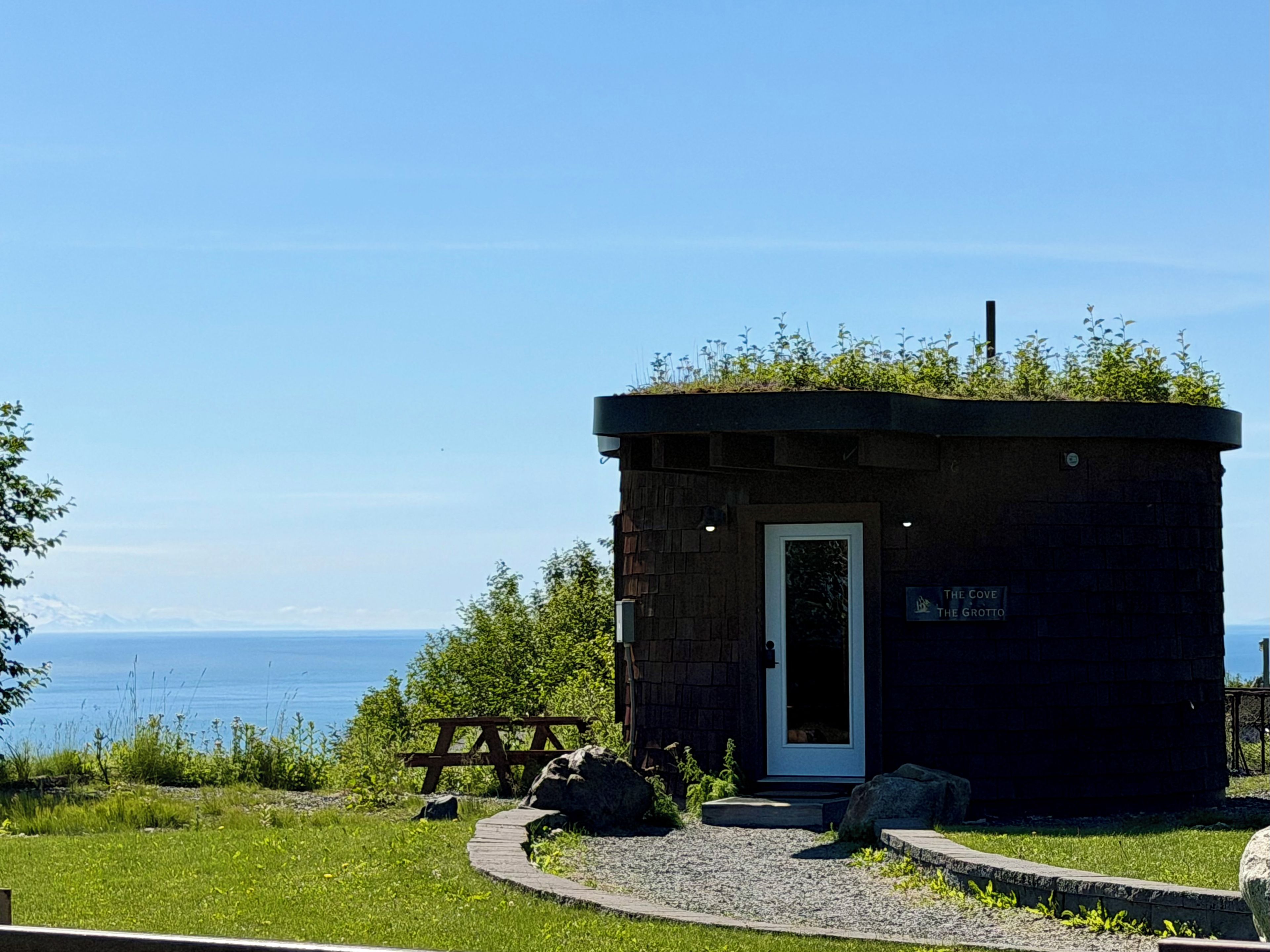 A small stone building with a door and a sign reading 'The Cove The Grotto.'