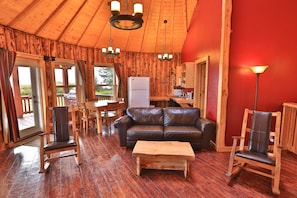 A wooden interior with a leather sofa, wooden rocking chairs, and a dining area. - Kenai Peninsula Suites (Homer)