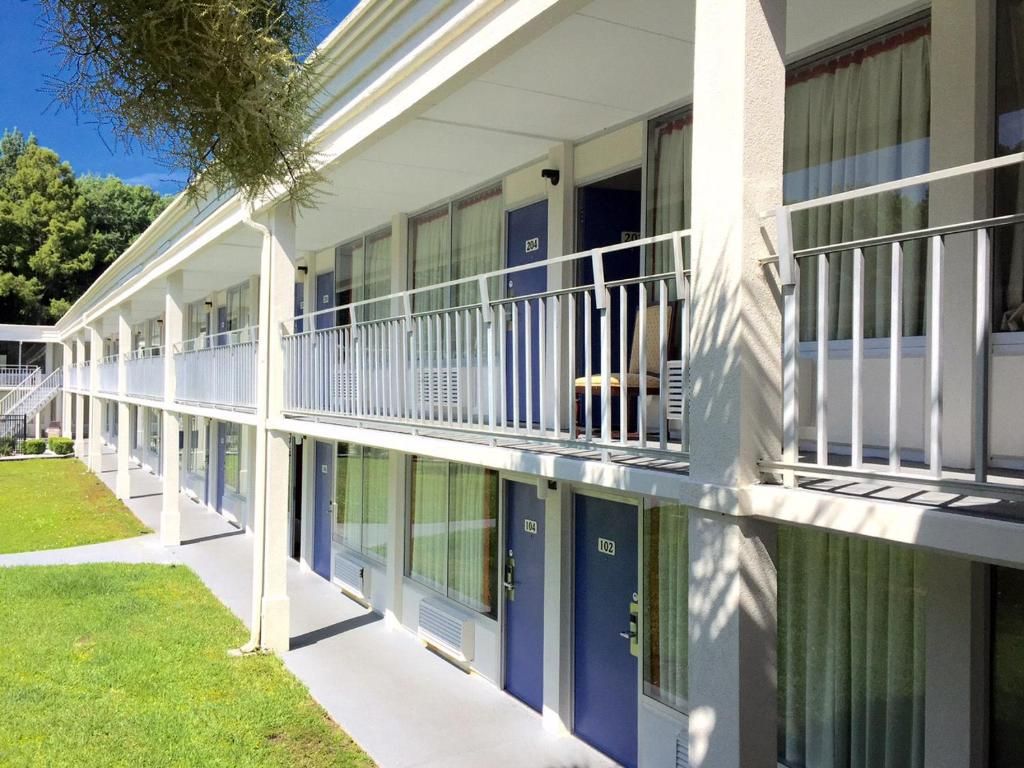A hotel with a covered outdoor area, multiple rooms with doors numbered 100 to 102, and a white railing along the balcony.