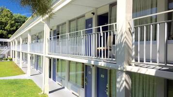 A hotel with a covered outdoor area, multiple rooms with doors numbered 100 to 102, and a white railing along the balcony.