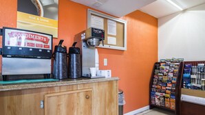 A coffee station with a coffee machine, two thermos flasks, a sugar dispenser, and a bulletin board with magazines. - Motel 6 Townsend, GA (Townsend)
