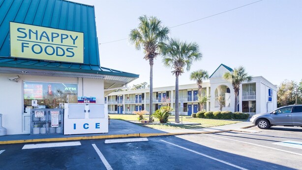 A motel with a 'SNAPPY FOODS' sign, a propane tank, and a 'TRIANGLE ICE' sign. - Motel 6 Townsend, GA (Townsend)