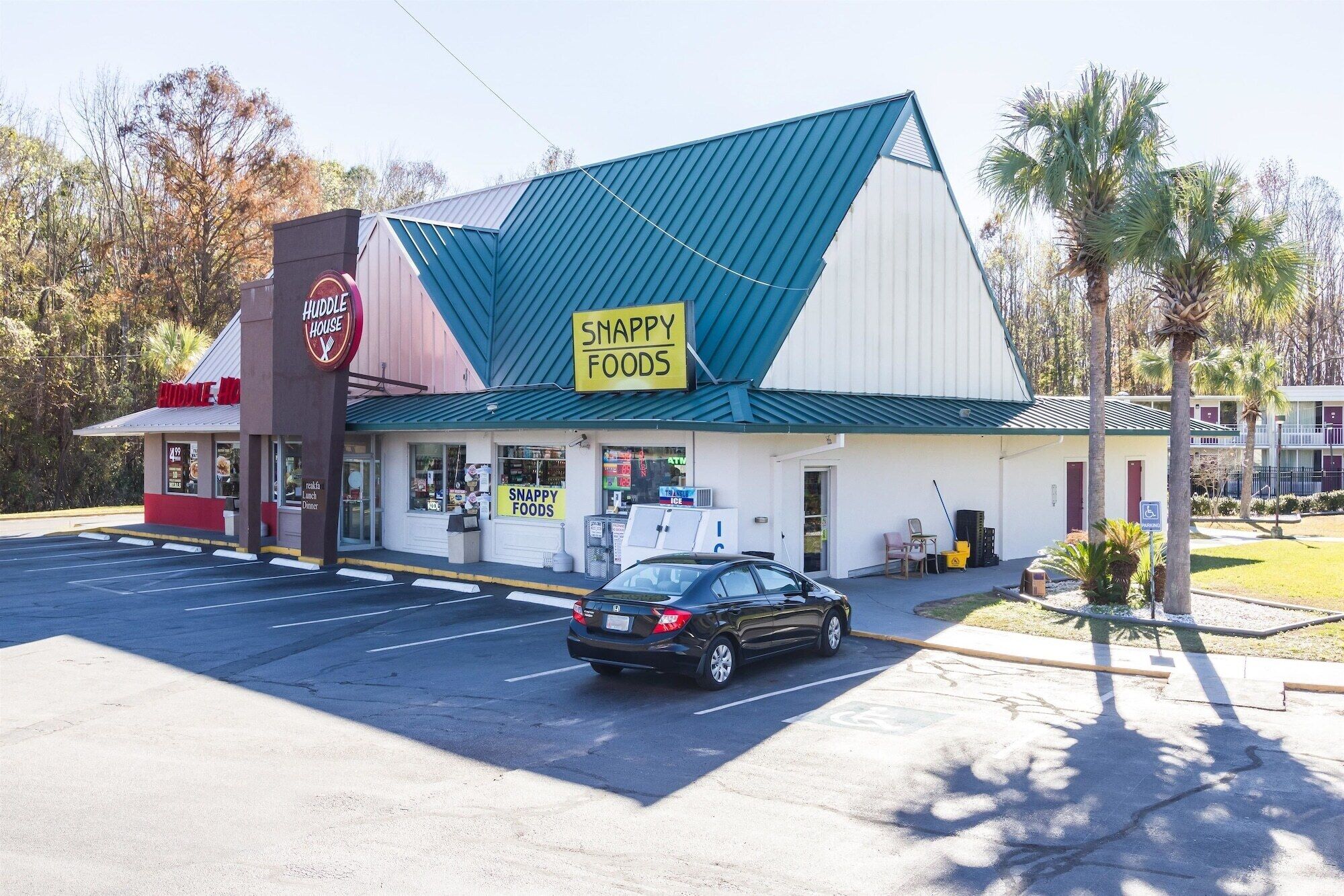 A Huddle House restaurant with a blue roof and a sign advertising 'SNAPPY FOODS'.