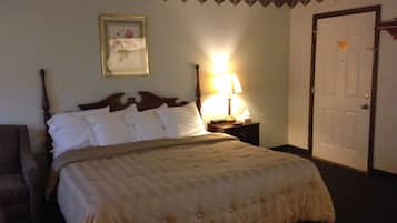 A neatly made bed with a wooden headboard, a bedside lamp, and a framed picture on the wall.