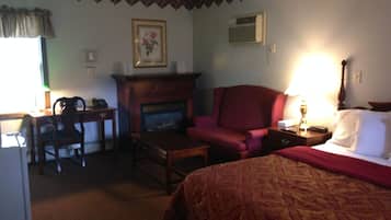 Habitación de hotel con cama, escritorio, sillón, chimenea y lámpara.
