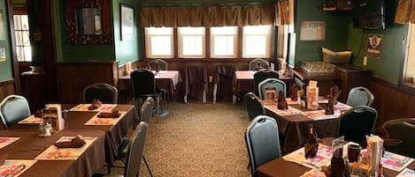 Comedor con mesas dispuestas para una comida, sillas y un ventilador de techo.