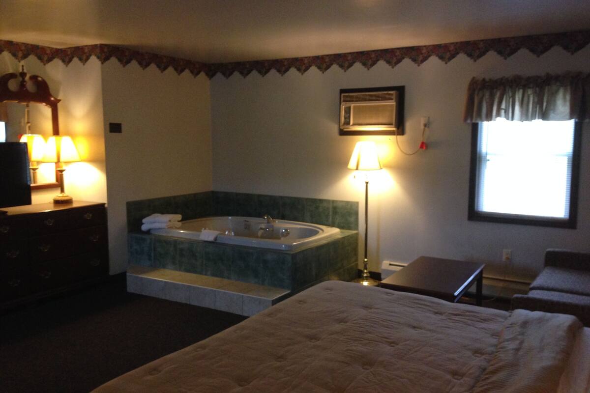 Une chambre d’hôtel avec un grand lit, une baignoire, un bureau et une fenêtre.