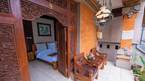 A traditional room with a bed, wooden furniture, and intricate carvings. - Teba House (Ubud)