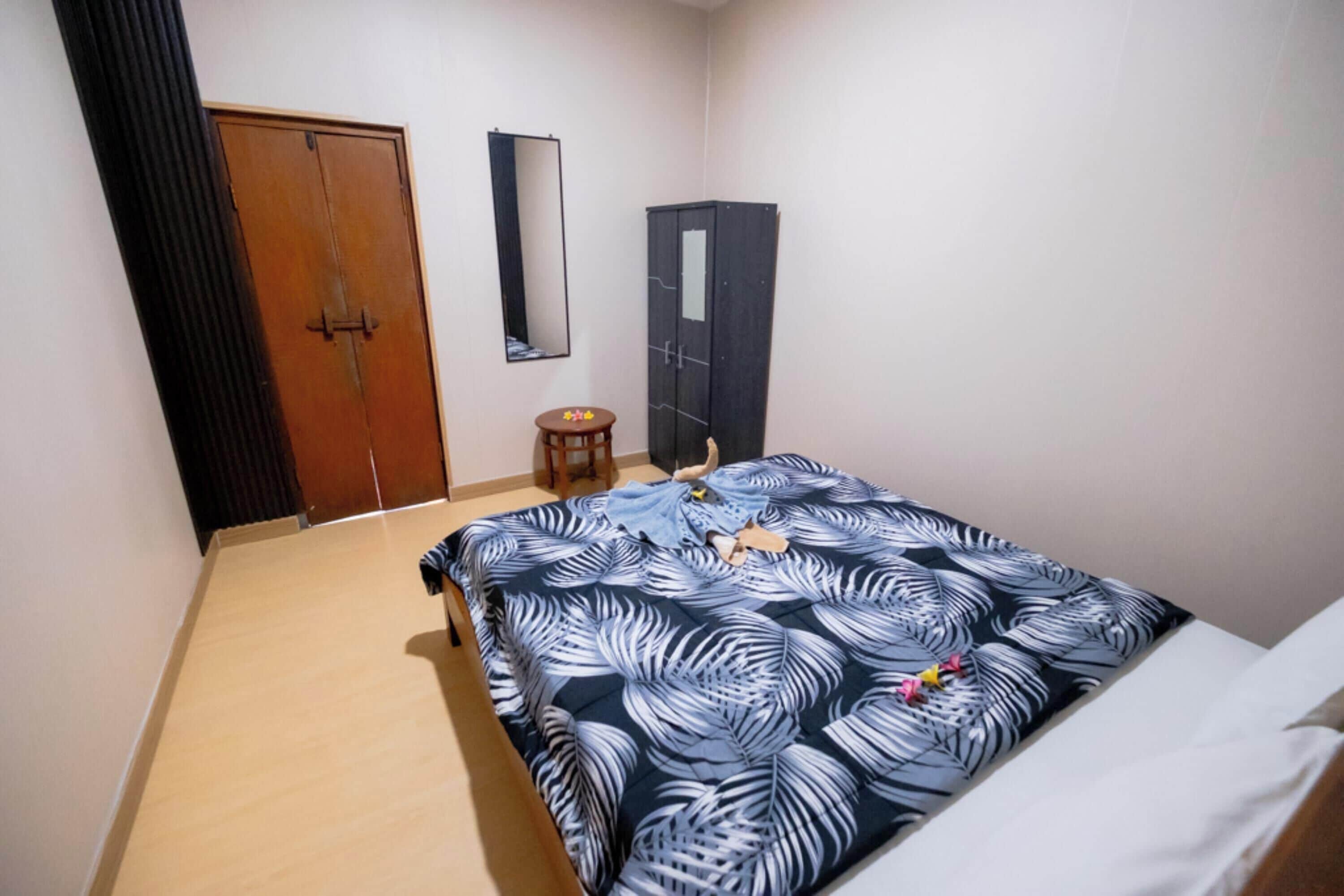Ein Schlafzimmer mit einem Bett, einem Kleiderschrank, einem Spiegel und einem kleinen Hocker.