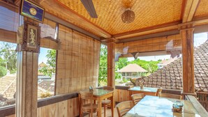 A wooden interior with bamboo ceiling, wooden tables and chairs, and large windows with bamboo blinds. - Teba House (Ubud)
