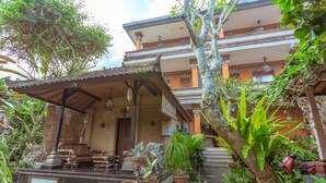A traditional building with a covered porch, potted plants, and a red scooter parked nearby. - Teba House (Ubud)