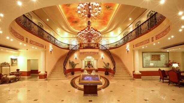 A grand lobby with a central staircase, a chandelier, and a reception area. - Tuli Imperial (Nagpur)