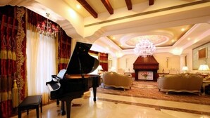 A grand room with a grand piano, ornate curtains, a chandelier, and classic furniture. - Tuli Imperial (Nagpur)