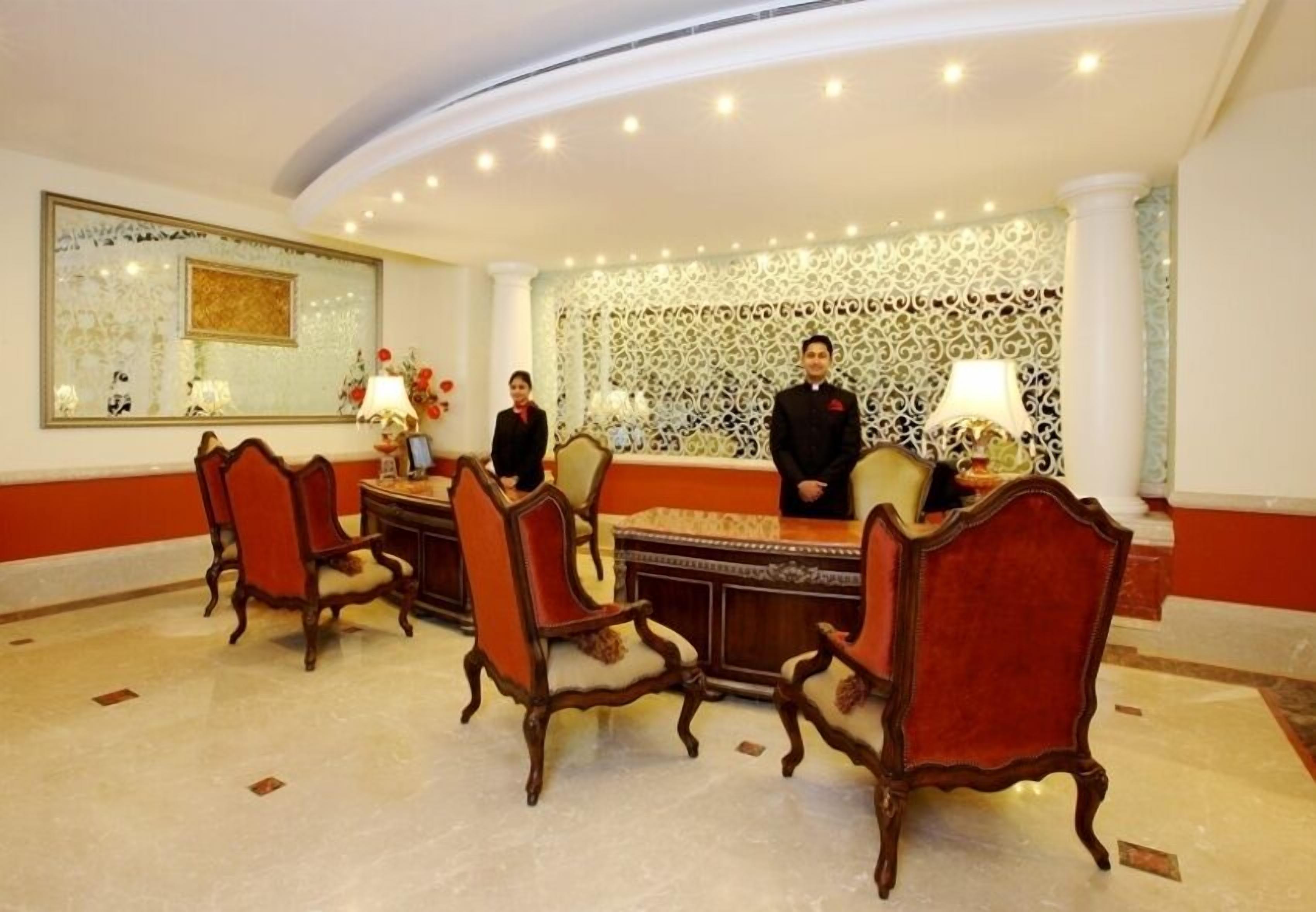 A reception area with a reception desk, several chairs, a large mirror, and decorative wall panels.