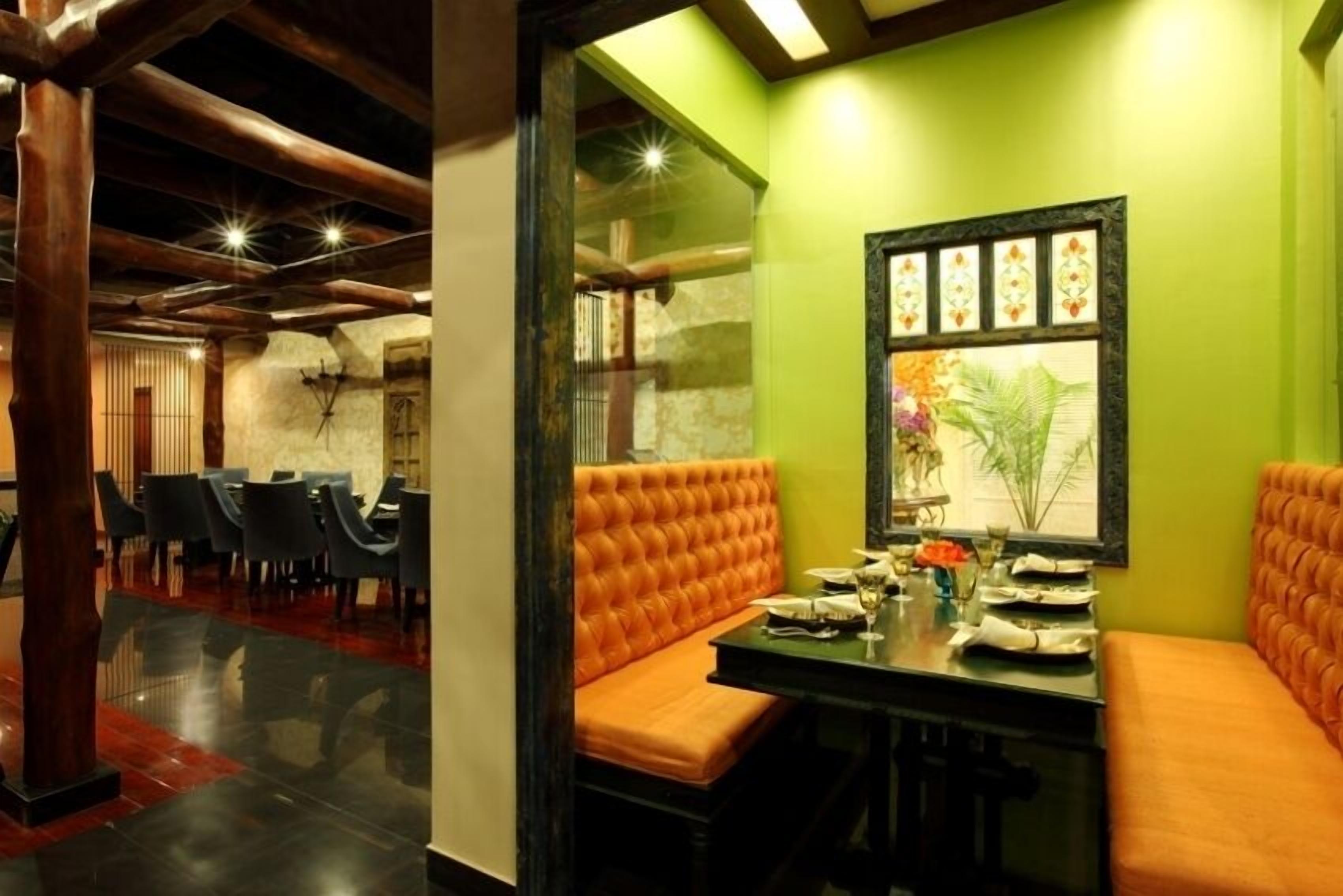 A restaurant with a green wall, orange cushioned seating, and a framed picture.