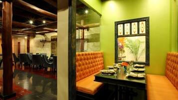 A restaurant with a green wall, orange cushioned seating, and a framed picture.