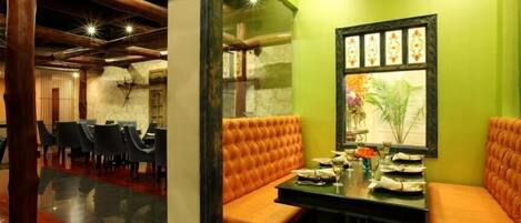 A restaurant with a green wall, orange cushioned seating, and a framed picture.