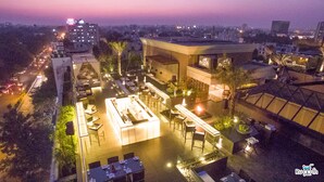 An aerial view of a rooftop restaurant with outdoor seating, surrounded by buildings and a cityscape at dusk. - Tuli Imperial (Nagpur)