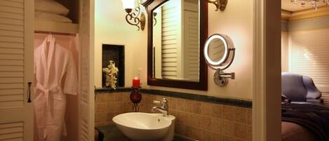 A bathroom with a white sink, a mirror with a round frame, and a towel rack with a white robe.