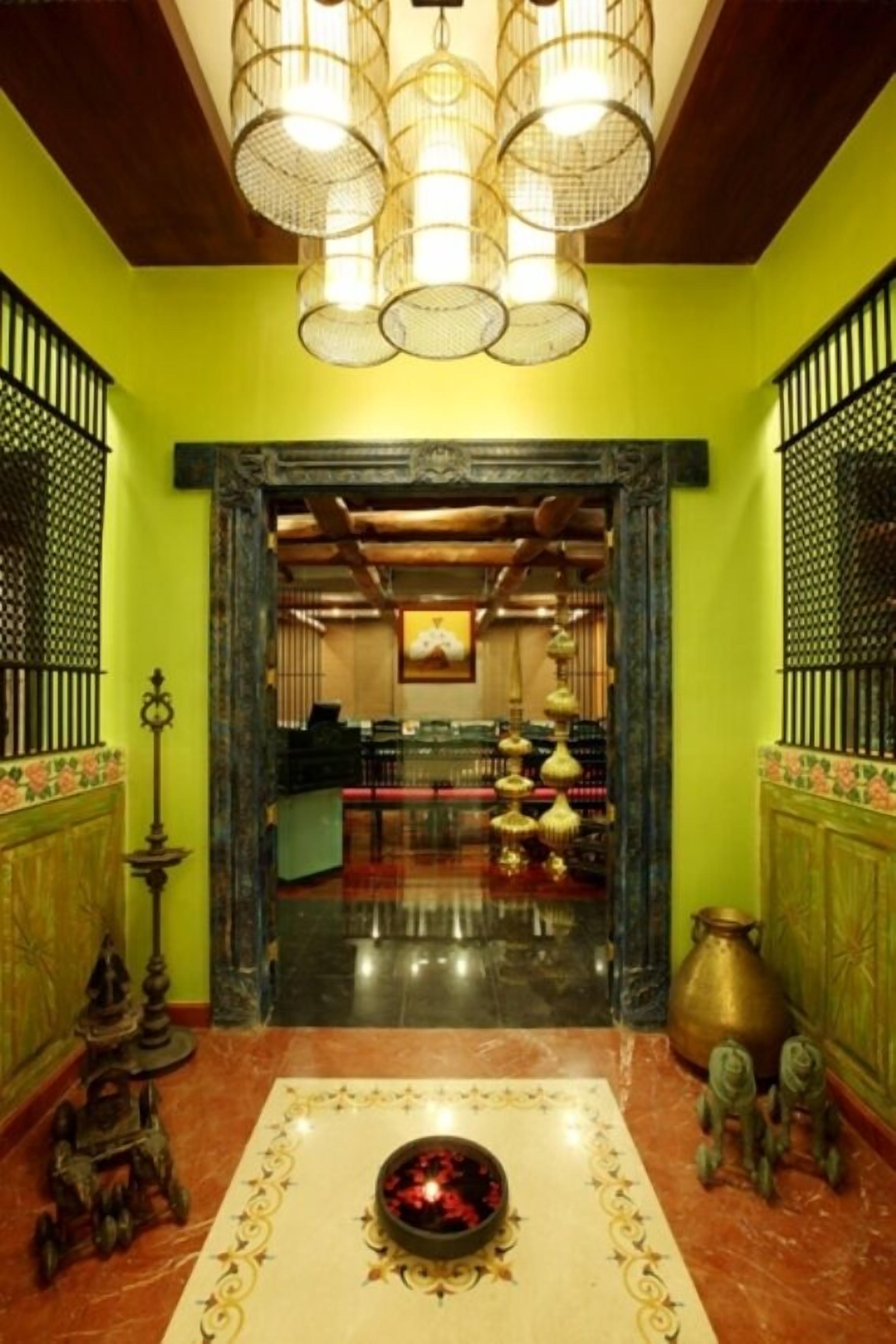Un vestíbulo con pared verde, una araña, una recepción y un elemento decorativo en el suelo.