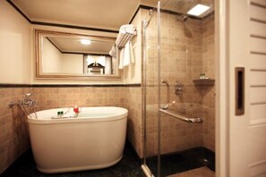 A bathroom with a freestanding bathtub, a glass-enclosed shower, and a mirror above the bathtub. - Tuli Imperial (Nagpur)