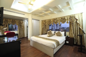 A hotel room with a large bed, a desk, a chair, and a view of the city. - The Nagpur Ashok (Nagpur)