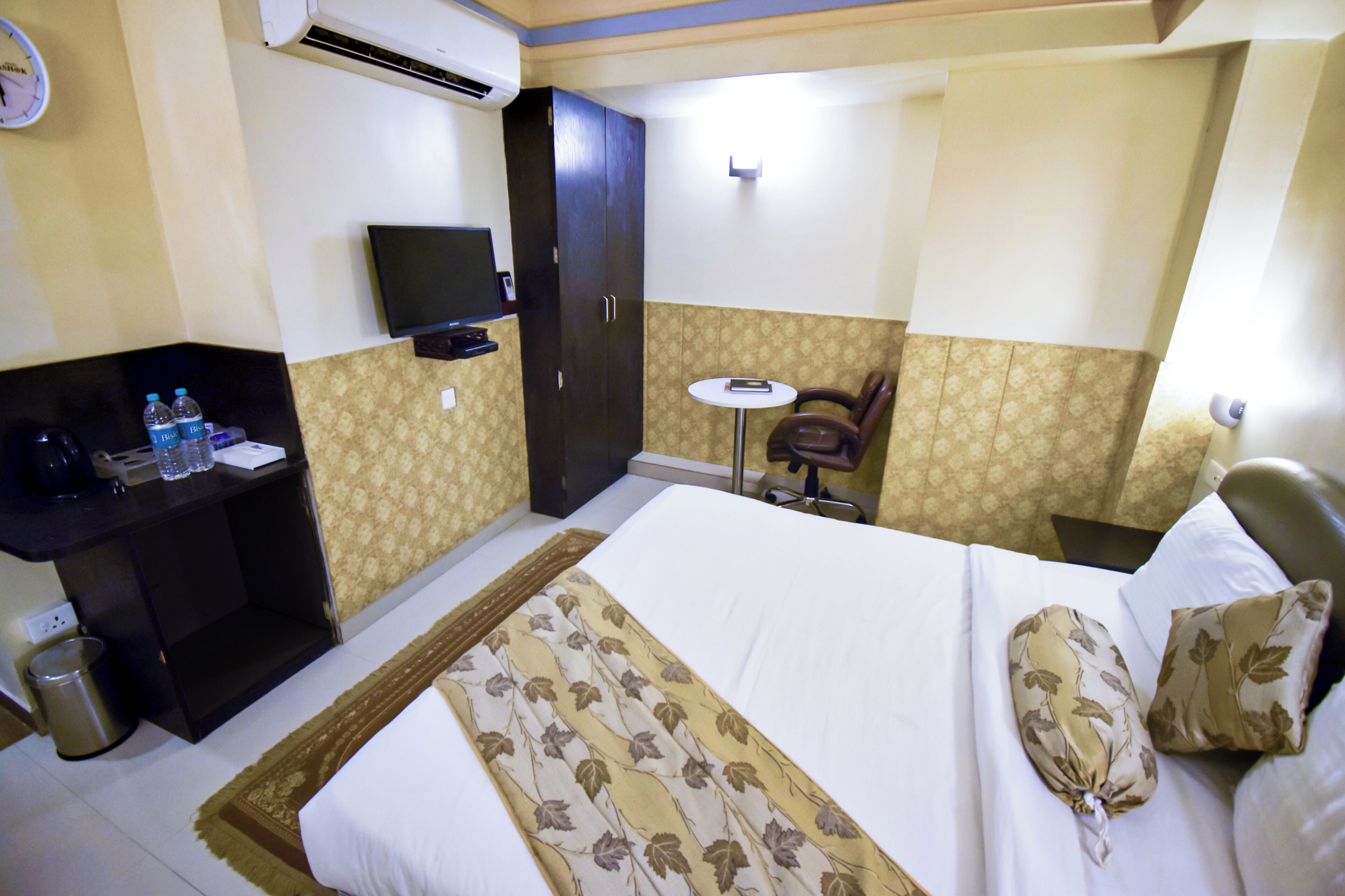 Una habitación de hotel con una cama, un escritorio con una silla, un televisor y una mesita.