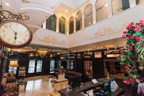 A lobby with a clock, seating, a reception desk, and decorative elements.